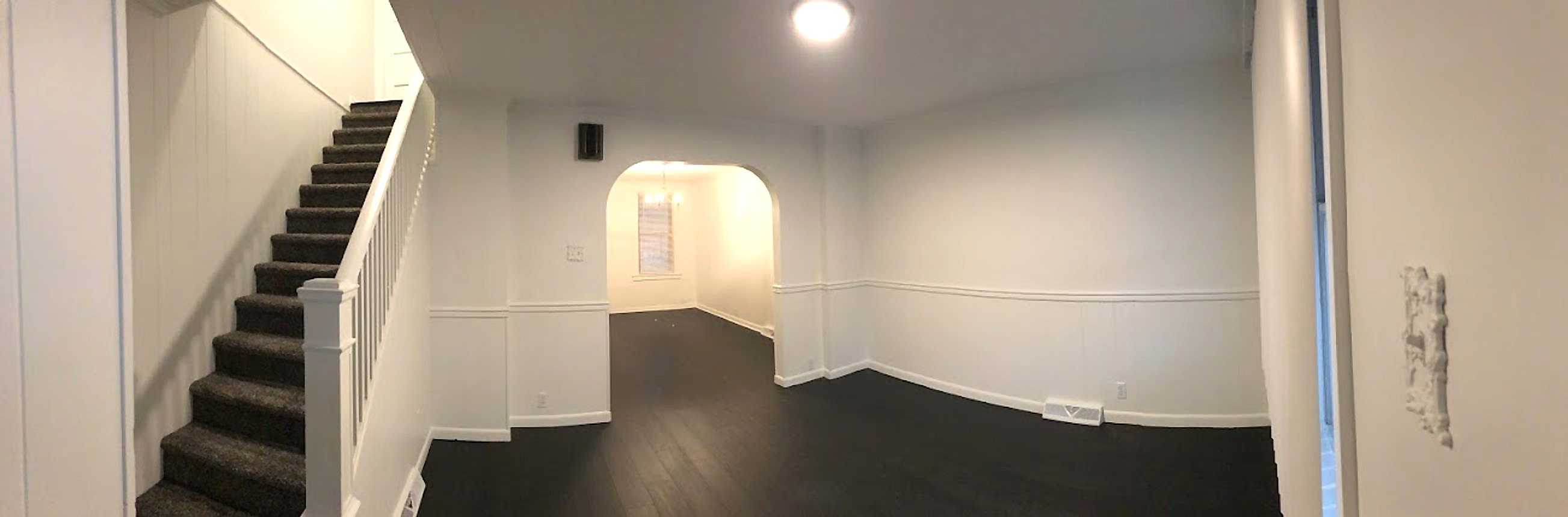 The same living room after painting, with white walls, wainscoting and stair railing