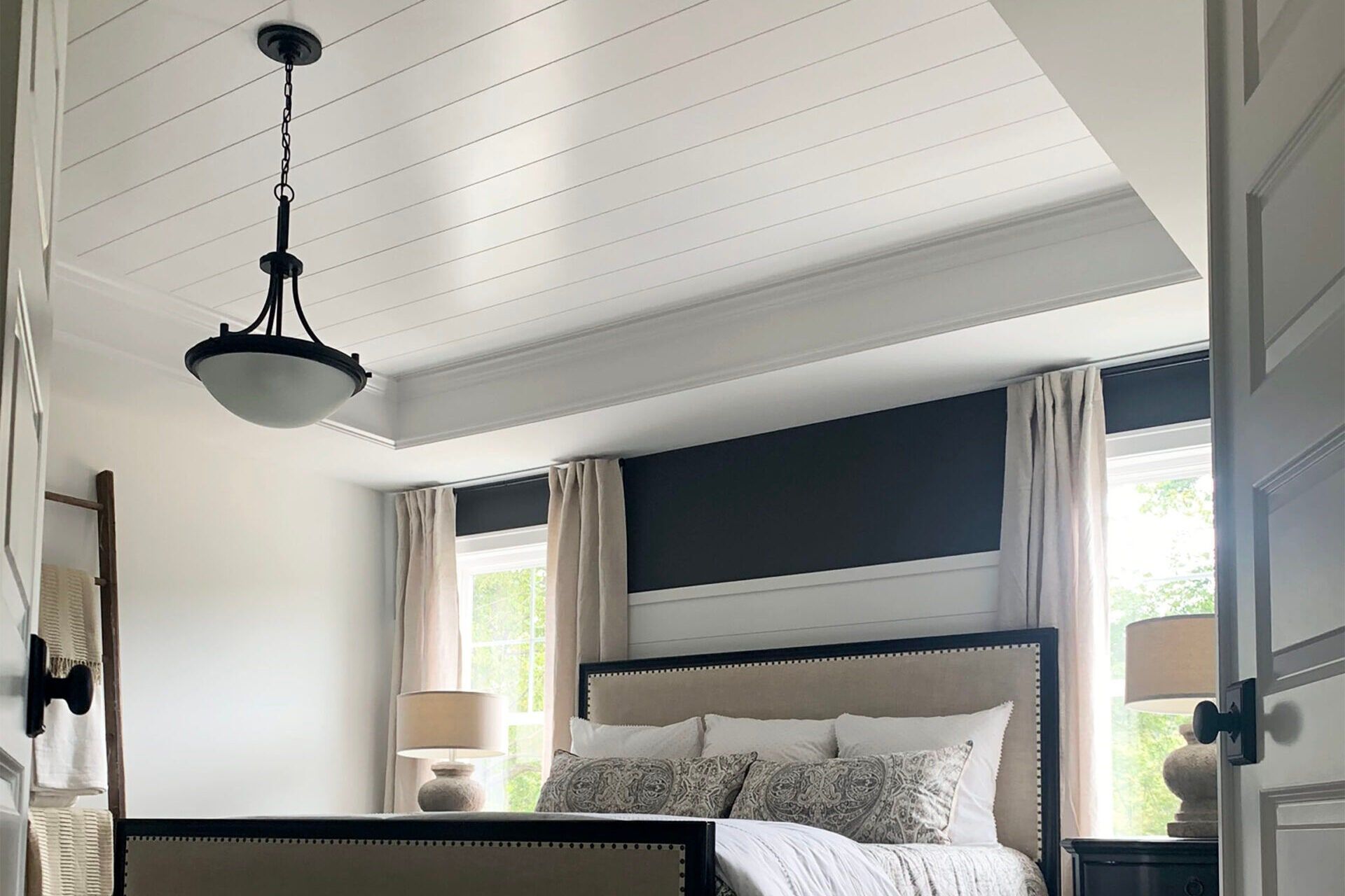Bedroom with a dark accent wall and white shiplap ceiling painted by Detail Painting Services