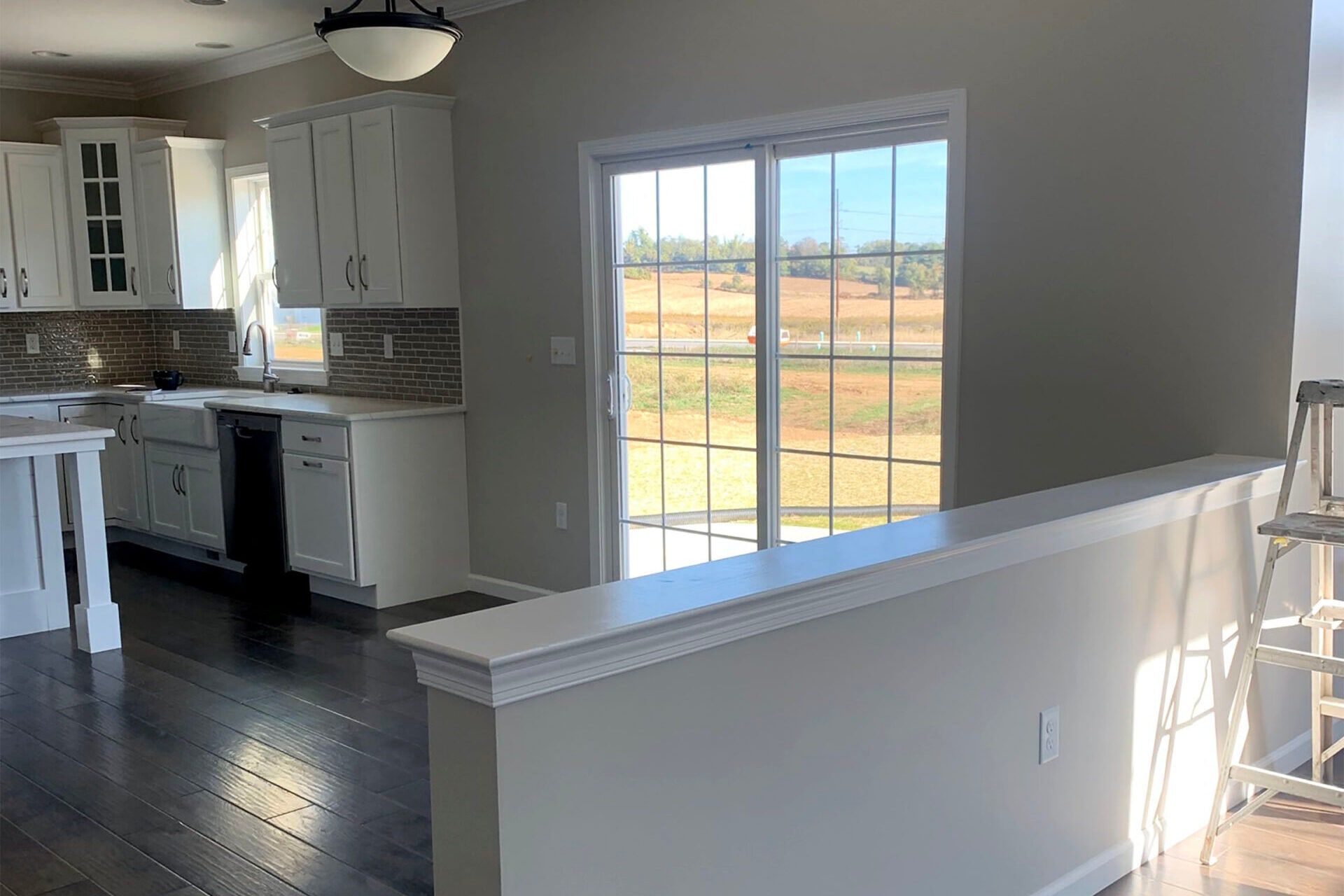 Kitchen with white painted cabinets, dark wood floors and a sliding door